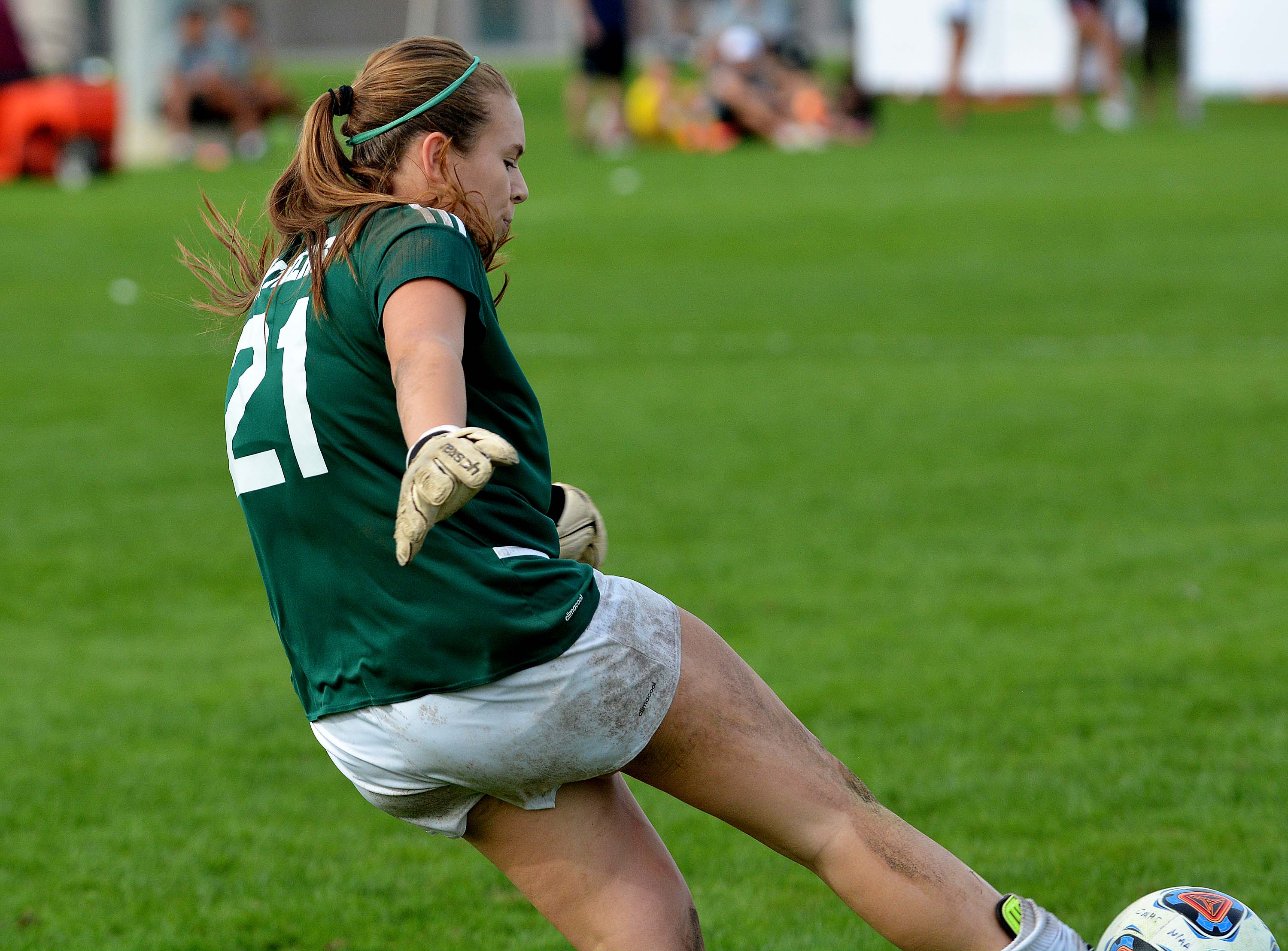 female soccer athlete kicking a soccer ball on a field of green grass